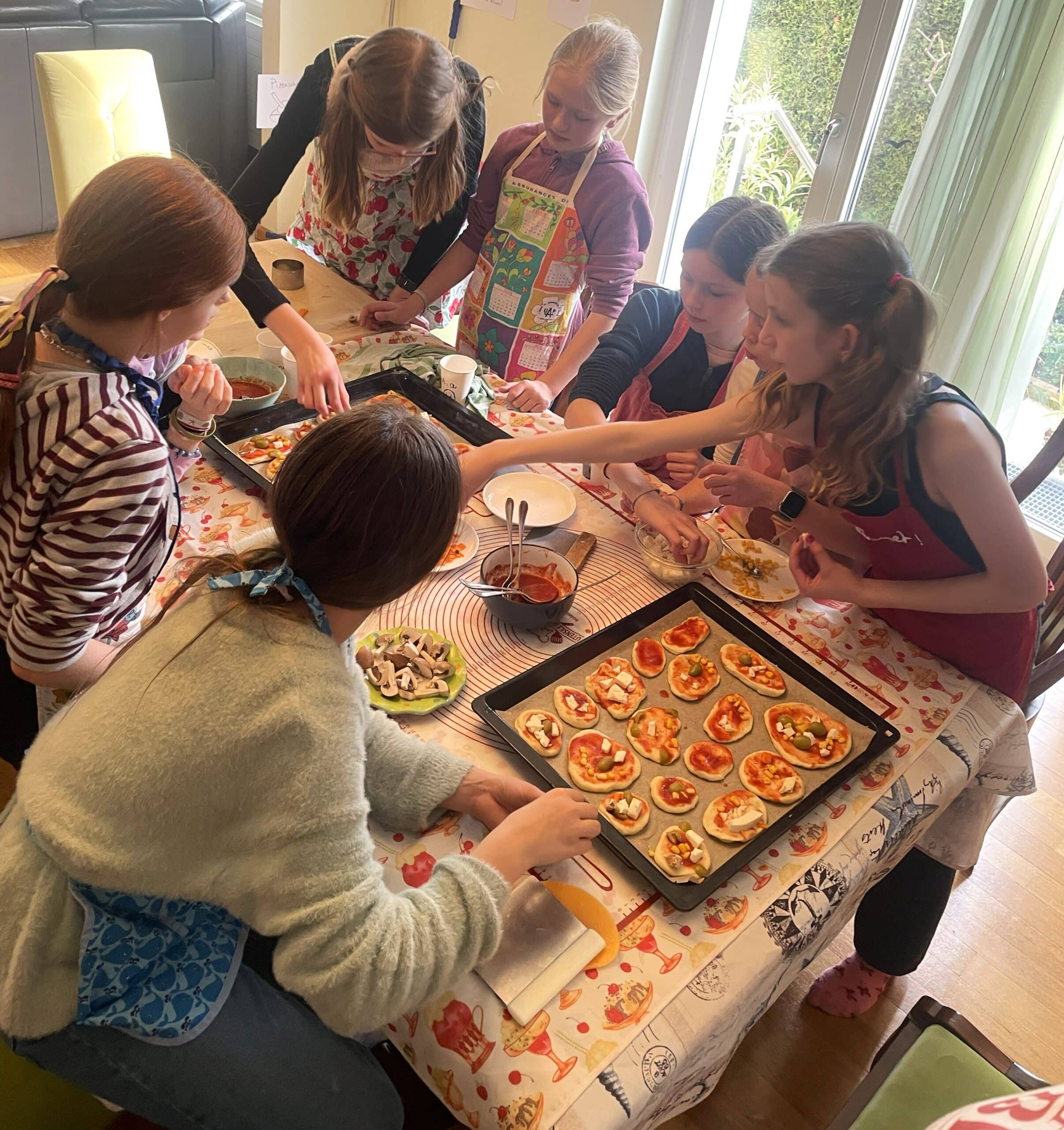 Kindergruppe die kleine und lustige Pizzen machen